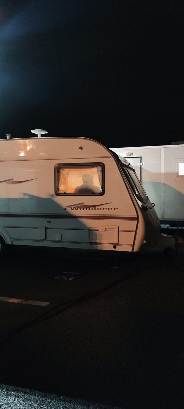 A parked Wanderer camper under night lights, perfect for a serene camping experience.